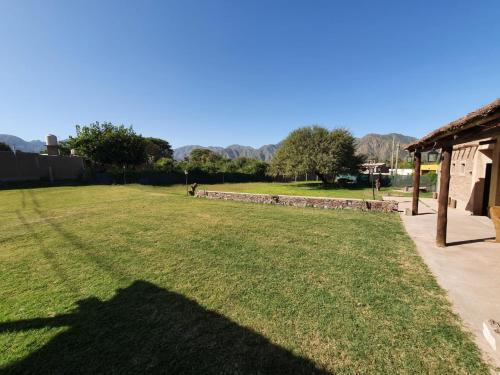 a large grassy yard with a stone wall at Huaco Casa de Campo in Belén