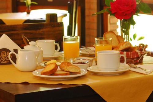 ein Tisch mit Tassen und Tellern mit Brot und Orangensaft in der Unterkunft Posada La Escondida in Villa General Belgrano