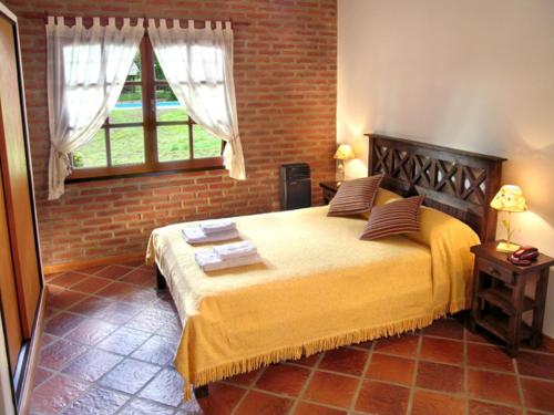 1 dormitorio con 1 cama grande y pared de ladrillo en Posada La Escondida en Villa General Belgrano