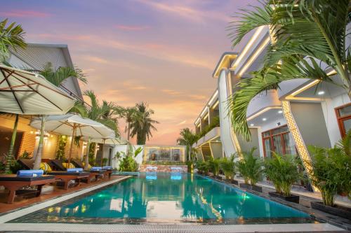 a swimming pool in the middle of a building with palm trees at Cambana La Rivière Hotel in Battambang