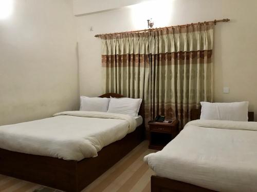 a room with two beds and a window at Hotel Asia in Pokhara