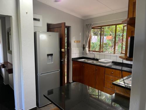a kitchen with a stainless steel refrigerator and a window at Umlalazi Cottage in Mtunzini
