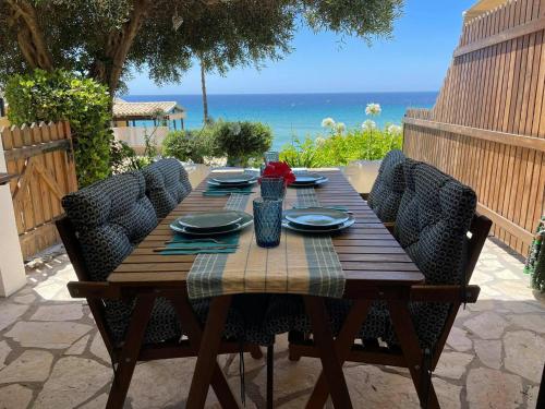 una mesa de madera con sillas y el océano en el fondo en Just my dream beachfront Home 34 in Glyfada beach Corfu by New Era en Glyfada