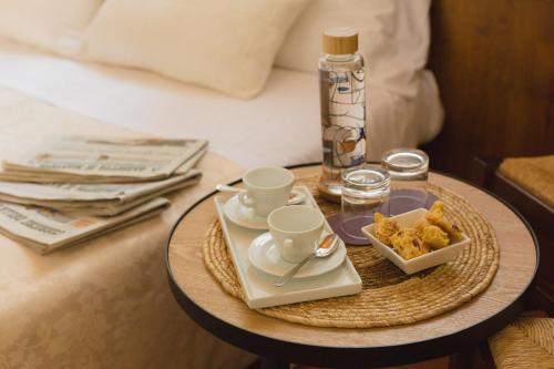 a table with two cups and a tray of food on a bed at Le Vigne di Adamo in Volta Mantovana