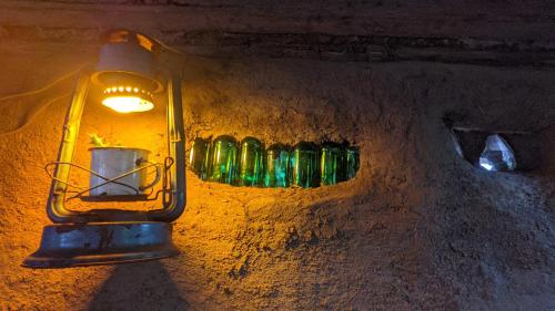 a light on the side of a wall with green bottles at Backyard Moshi Eco Bungalows in Moshi
