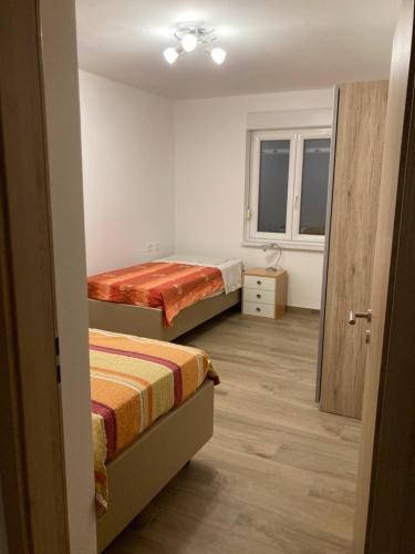 a small room with two beds and a window at First Vrtovin Apartment in Črniče