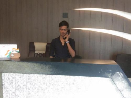 a man talking on a cell phone in a mirror at Hotel Guestinn Residency in Mumbai