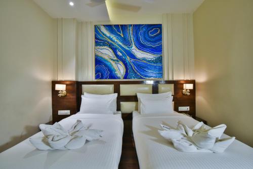 two beds in a room with a painting on the wall at Hotel BR Grand With Nimo Club Amritsar -5 Mint From Golden Temple in Amritsar