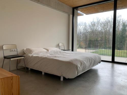 Dormitorio blanco con cama y ventana grande en Casa de Tartera, en Olot