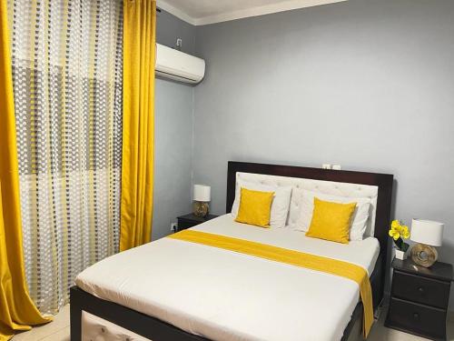 a bedroom with a large bed with yellow pillows at Appartement meublé haut standing Bonamoussadi (Kotto) in Douala