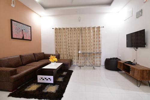 a living room with a couch and a tv at Xcel Luxury Hotel Apartments-Home Living Redefined in Mysore