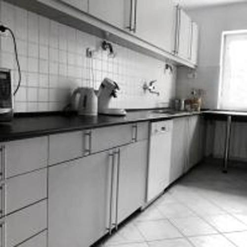 a kitchen with white cabinets and white tiles at Villa Alexandra Szentantalfa in Szentantalfa