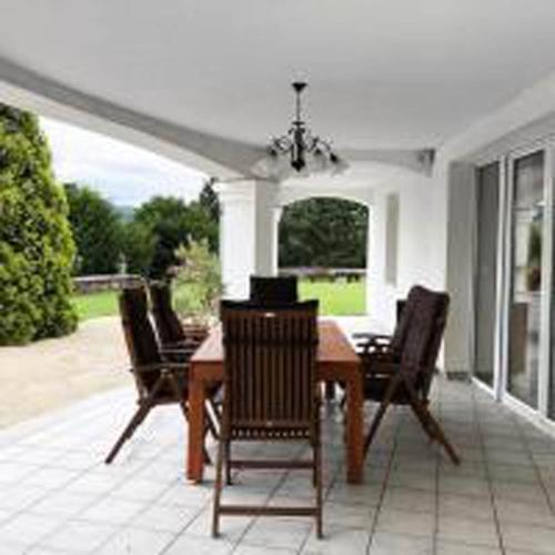 a dining room with a table and chairs on a patio at Villa Alexandra Szentantalfa in Szentantalfa