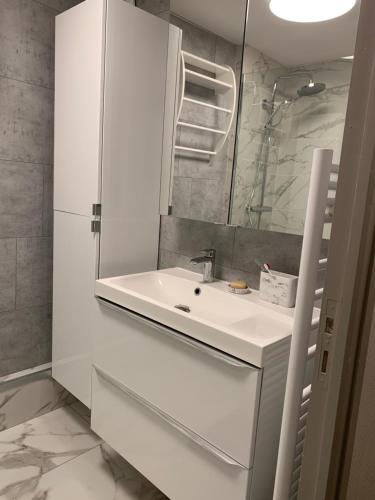 une salle de bain blanche avec un lavabo et un miroir dans l'établissement Fort-Mahon Plage : Superbe appartement vue mer, à Fort-Mahon-Plage