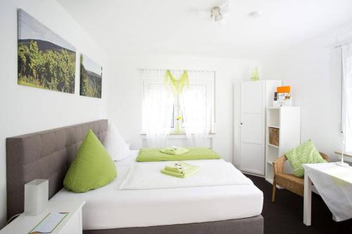 Cette chambre blanche dispose d'un lit avec des oreillers verts. dans l'établissement Hotel Emmerich, à Winningen