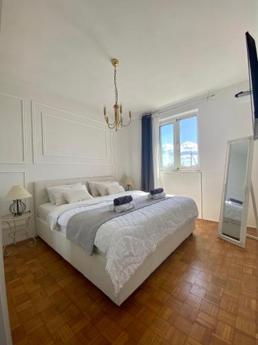 a white bedroom with a large bed with a chandelier at Beautiful island house Ugljan in Ugljan