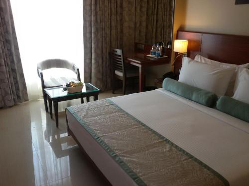 a hotel room with a bed and a chair and a table at Hotel Green Olive in Aurangabad