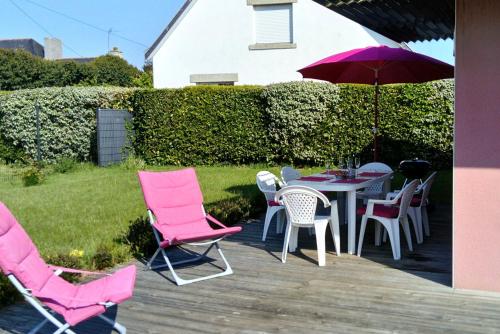 a patio with pink chairs and a table with an umbrella at Gîte, Plain-pied, label Gites de France et Clevacances in Tréffiagat
