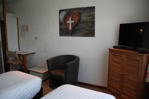 a room with a bed and a chair and a television at Hotel Halleux in Banneux