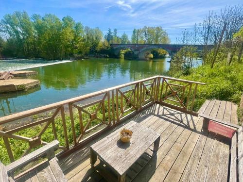 una terraza de madera con una mesa junto a un río en Moulin d'Albias aux portes de Montauban, en Albias