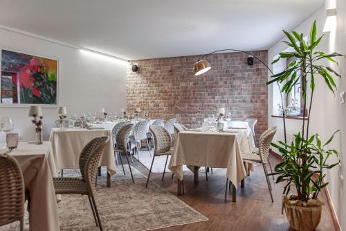 een eetkamer met tafels en stoelen en een bakstenen muur bij Cardo Boutique&Wine Resort in Málchina