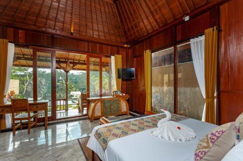 a bedroom with two beds and a table with a television at Campuhan Sebatu Resort in Tegalalang