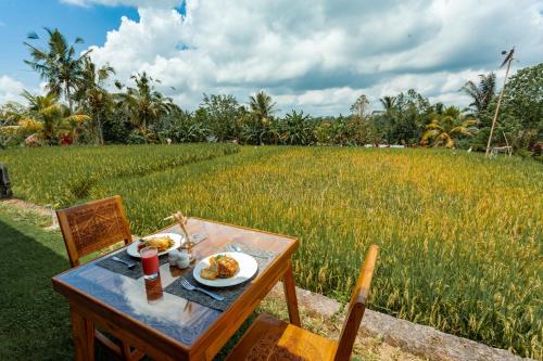 ein Tisch mit einem Teller Essen vor einem Feld in der Unterkunft Campuhan Sebatu Resort in Tegalalang
