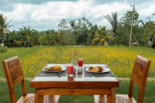 ein Holztisch mit zwei Tellern Essen und ein Feld in der Unterkunft Campuhan Sebatu Resort in Tegalalang