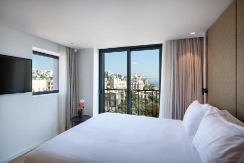 a bedroom with a white bed and a large window at Sofia Hotel Sea Of Galilee in Tiberias