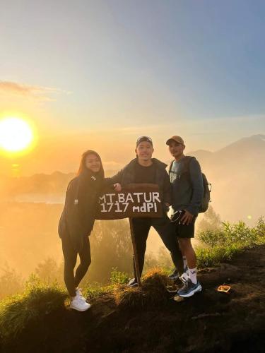 a group of three people standing on top of a mountain at Batur lake view in Kintamani