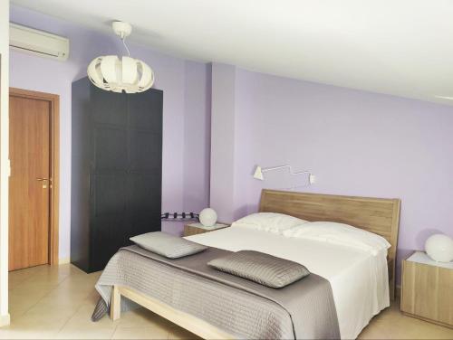 a bedroom with a large bed with purple walls at La Scivola Rooms in Acitrezza