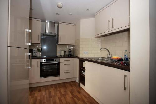 una cocina con armarios blancos y electrodomésticos de acero inoxidable en Salisbury Luxury Apartment en Salisbury