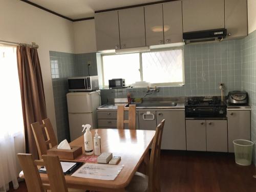 uma pequena cozinha com uma mesa de madeira, uma mesa e cadeiras em Golden Mile Apartment em Amami