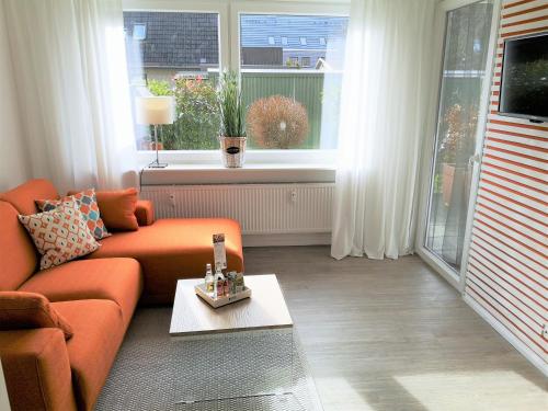 ビューズムにあるButze Ferienapartmentのリビングルーム(オレンジ色のソファ、窓付)