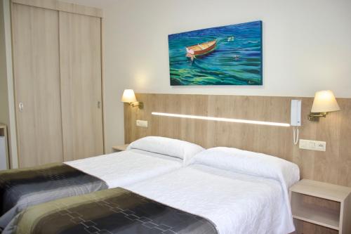 a hotel room with a bed and a painting of a boat at Hotel Playa de Lago in Muxia