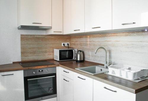 a kitchen with white cabinets and a sink and a microwave at Apartment Paić in Kaštela