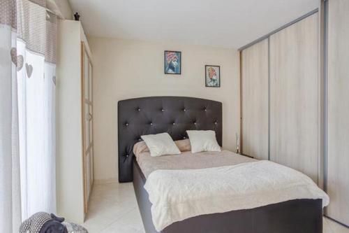 a bedroom with a large bed with a black headboard at APPARTEMENT LA GRANDE MOTTE (34280) in La Grande-Motte