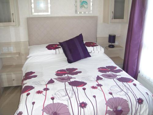 ein Schlafzimmer mit einem Bett mit roten Blumen darauf in der Unterkunft Bri-ann's Seaside Holiday Home NO VANS OR LARGE VEHICLES in Selsey