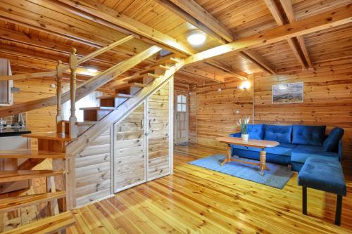 a log home living room with a blue couch and a table at Słoneczny Brzeg Polańczyk Domki 8-osobowe in Polańczyk