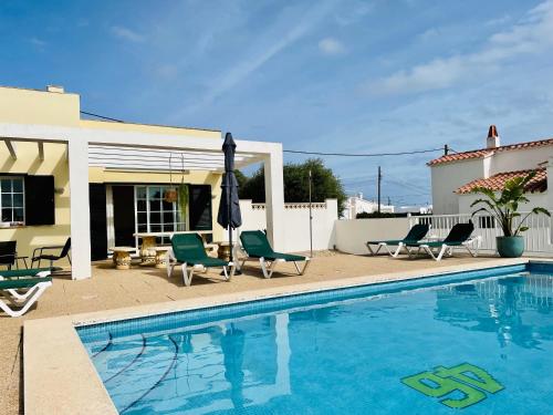 uma piscina com cadeiras e um guarda-sol ao lado de uma casa em Villa Jordi - Cala en Porter em Cala'n Porter