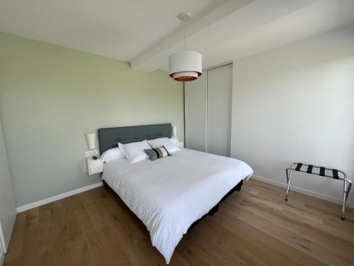 a white bedroom with a large bed with white sheets at résidence belle vue in Fontaine-le-Port