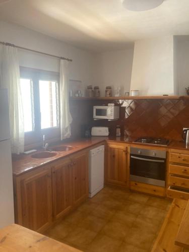 a kitchen with wooden cabinets and a sink and a microwave at Can Che in Cala Galdana