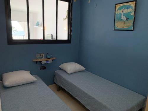 two beds in a room with blue walls and a window at AwayDays - BI - 41 in Empuriabrava