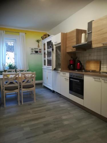 a kitchen with white cabinets and a table with a dining room at Ferienwohnung zur alten Post in Bad Grund