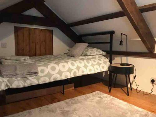 1 dormitorio con 1 cama grande y 1 mesa en Woodland cottage in Cornwall with walled garden en Helston