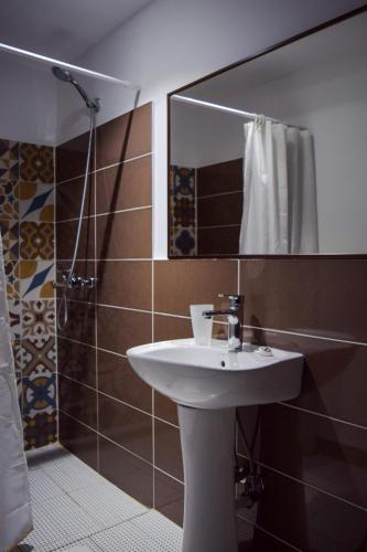a bathroom with a sink and a shower with a mirror at Sokaku i te Marreve GuestHouse in Gjirokastër