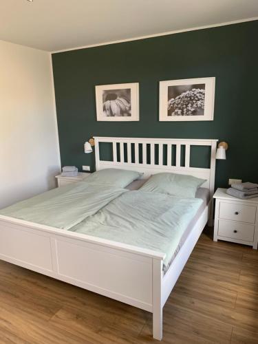 1 cama blanca en un dormitorio con una pared verde en Lille Hygge, en Clenze