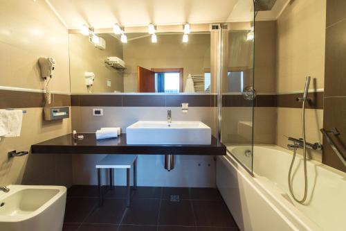 a bathroom with a sink and a tub and a mirror at Hotel Villa Giulietta in Fiesso dʼArtico