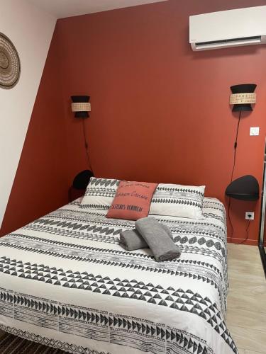 een bed in een kamer met een rode muur bij Studio Cosy tt confort proche aéroport in Colombier-Saugnieu