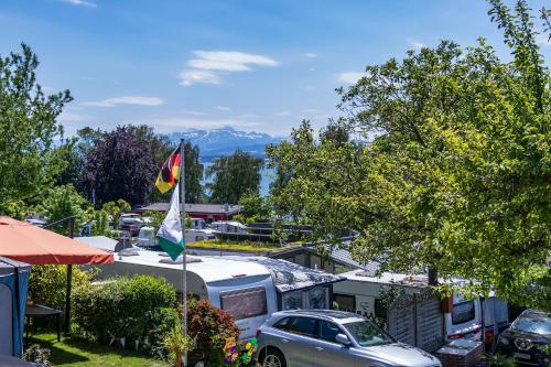 a view of a parking lot with a caravan and a flag at Campingplatz Alpenblick in Hagnau